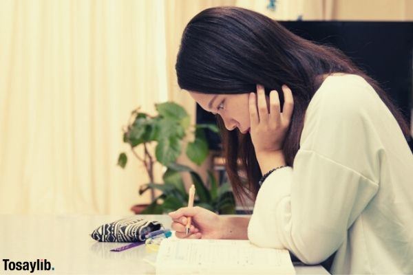 girl studying holding a pen writing and holding her hair