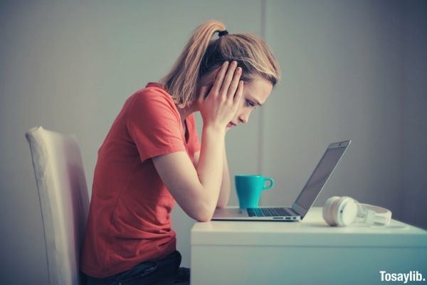 04 young woman troubled using laptop at home blue mug