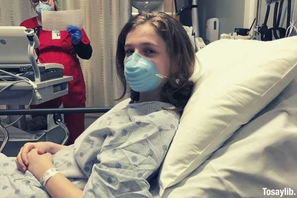 woman lying on hospital bed wearing mask