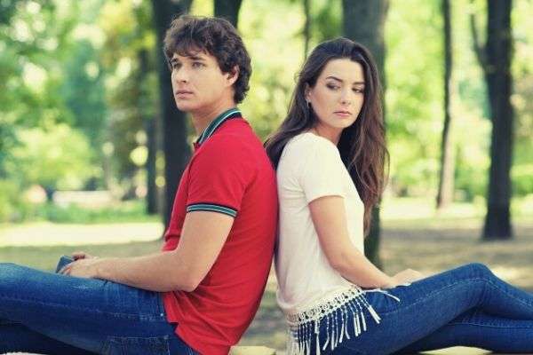 couple sitting back to back on the bench at the park