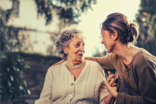 joyful-adult-daughter-greeting-happy-surprised-senior-mother-in-garden