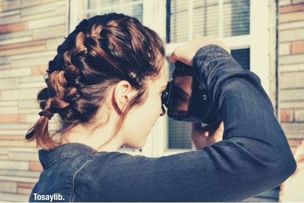 woman with braided hair taking photo DSLR camera