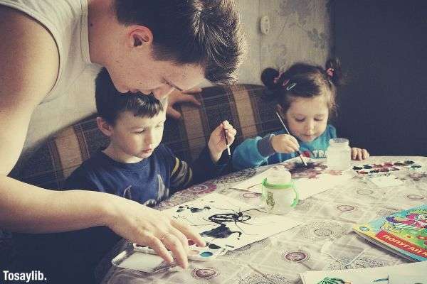 Happy children painting on top of the table with dad