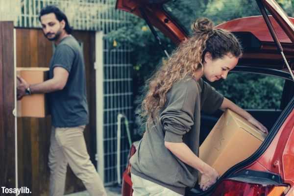 modern couple unpacking car while moving to new place orange car boxes
