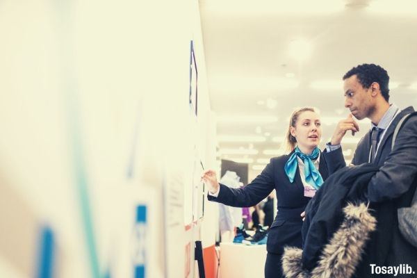 photo of a woman talking explaing something to the man near the wall