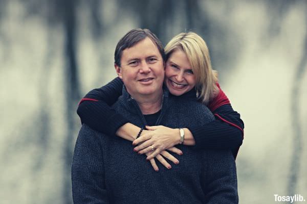 woman in black sweater hugging man in black sweater while standing