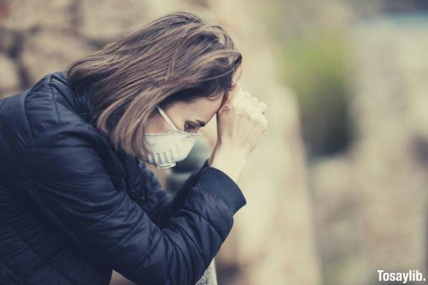 woman in black leather jacket sitting wearing white face mask