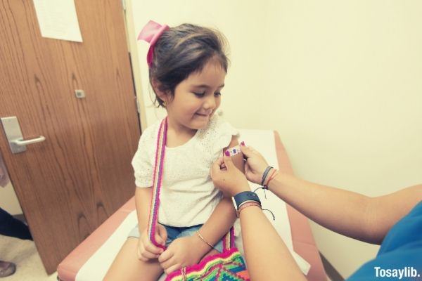 cute girl getting vaccine and doctor putting cute sticker band aid