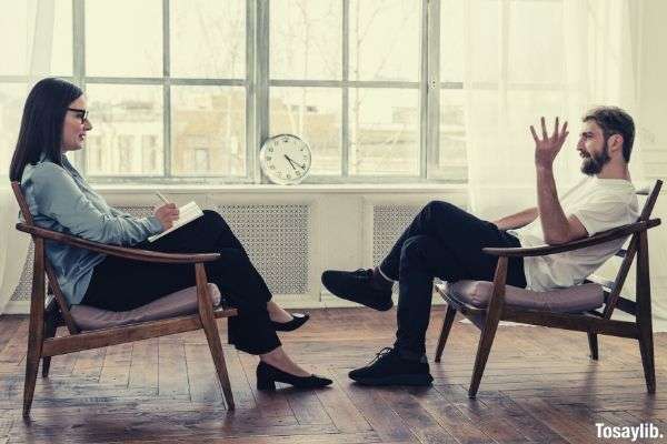 person man woman sitting on brown wooden chair interview clock