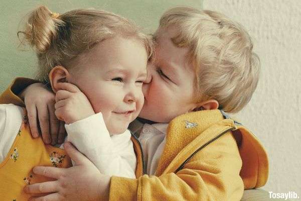 cheerful little siblings hugging in armchair at home