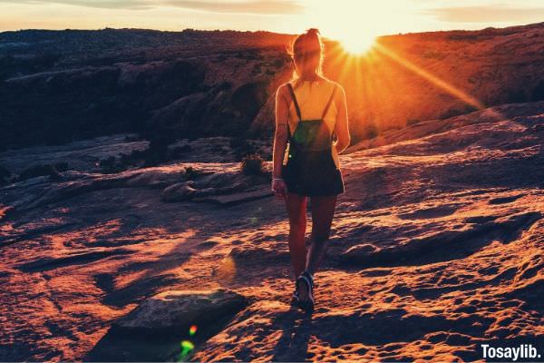 woman in top tank with backpack hiking sunset