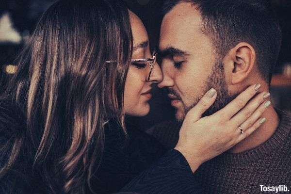 woman black sleeves trying to kiss man in brown shirt