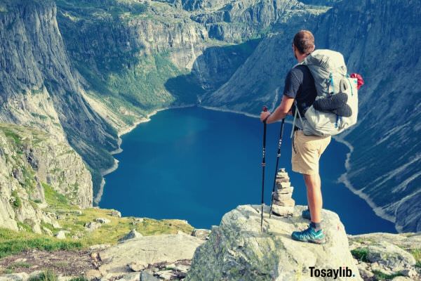 man standing on the rock while looking at the lake