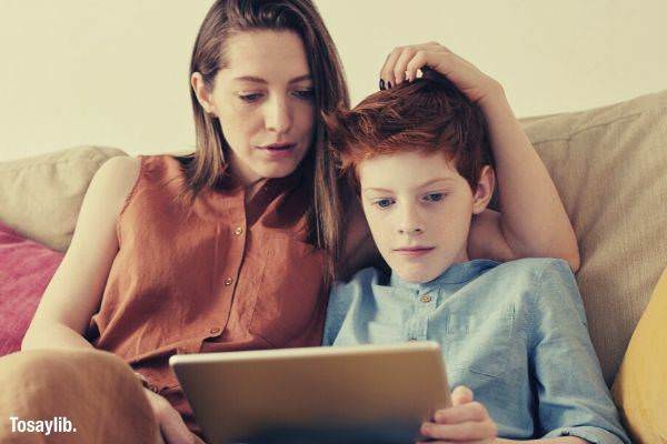 01 photo of woman and boy watching through tablet computer sofa