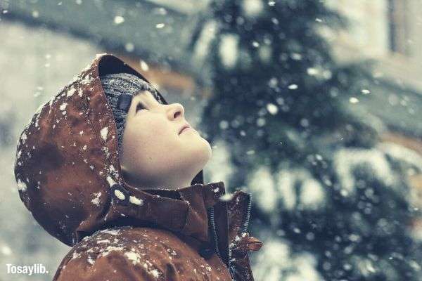 03 boy marvels at falling snow brown coat