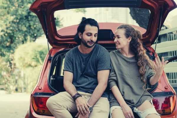 young diverse couple relaxing after unpacking car while moving home indian american