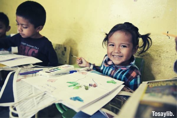 girl with tied hair smiling while painting holding a paint brush