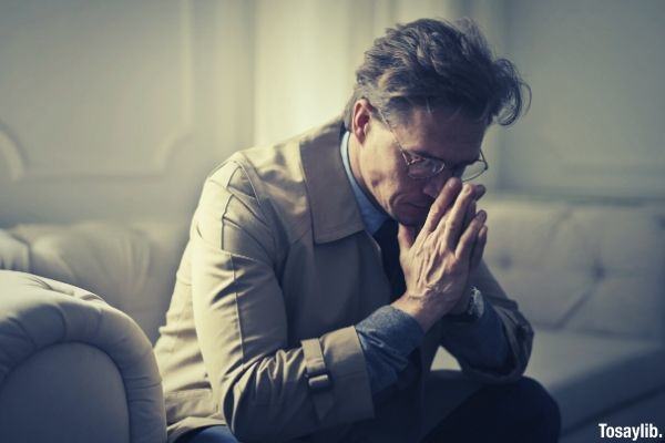 sad mature businessman thinking about problems in living room wearing suit and eyeglass