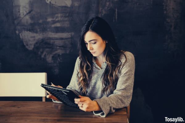 woman wearing gray long sleeves holding ipad while sitting