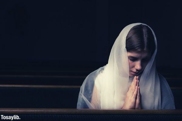 woman with white scarf praying black background