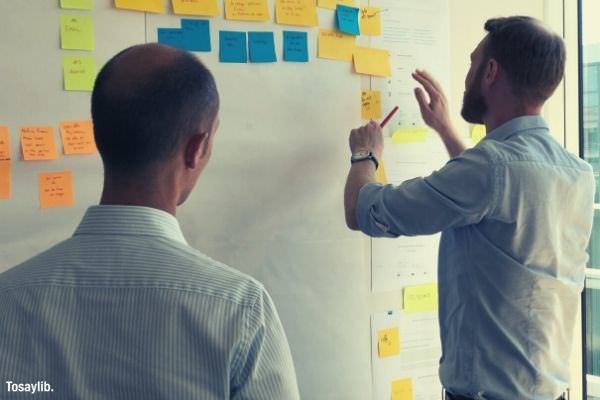 bearded man in polo formal facing wall with lots of sticky notes