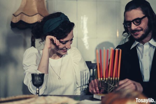 couple love man putting candles on the table woman looking at him