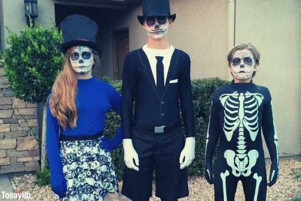 kids wearing halloween costumes outside the house girl on blue boy on black and another boy in skeleton