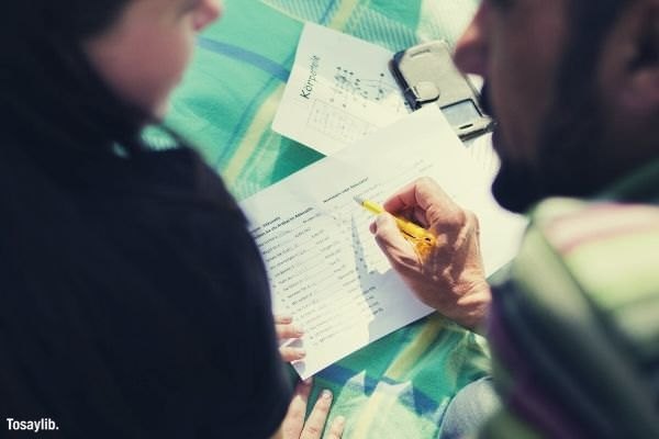 bearded man sitting beside a girl pointing something on the paper