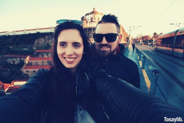 travelling couple love smiling selfie wearing black jackets with sunglasses