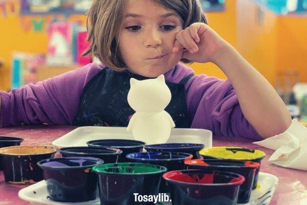 short haired kid wearing violet long sleeves wearing apron thinking what color to use