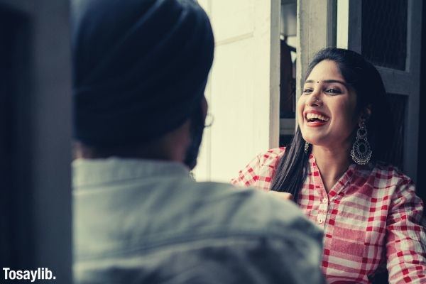 trendy young woman with dangling earrings laughing at joke told by man