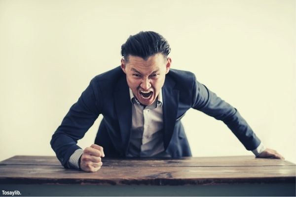 mad formal executive man yelling at camera fis on brown table