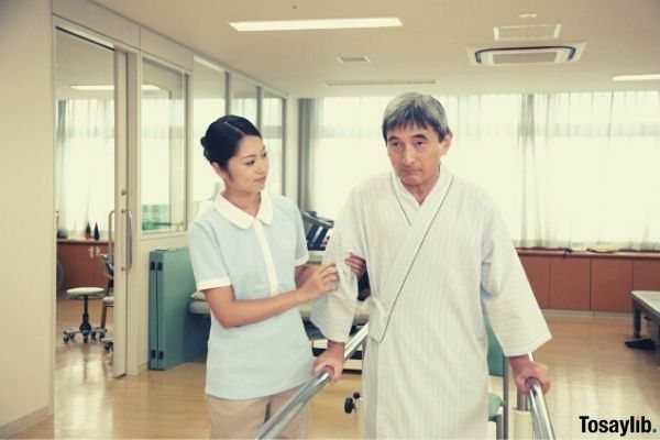 physical therapist helping an old patient walk