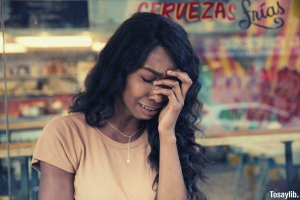 black woman crying wearing necklace and beige shirt