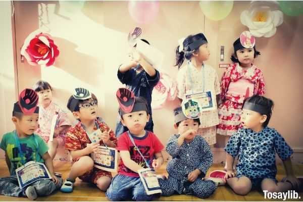 group of japanese kids sitting and standing wearing different costumes and masks