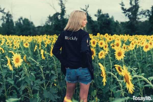 woman in black sweater standing on the sunflower field