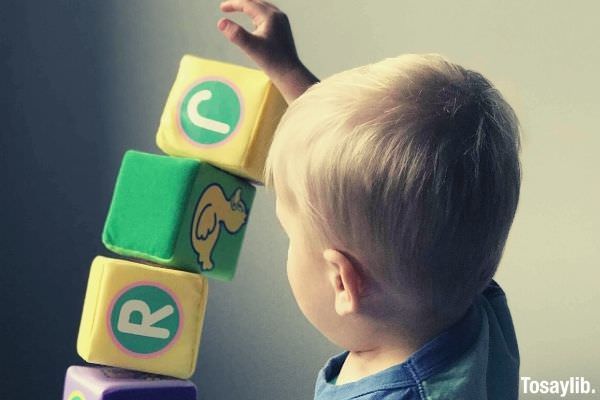 little boy playing soft cubes on a white wooden table