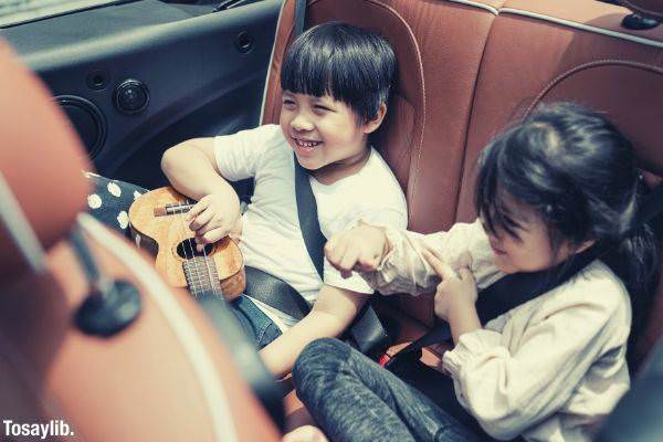 two happy asian traveling in the car boy holding ukulele