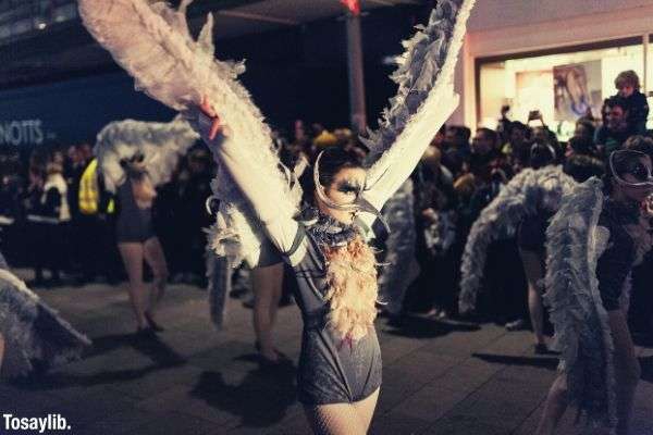 woman wearing gray with wings raising her arms on parade