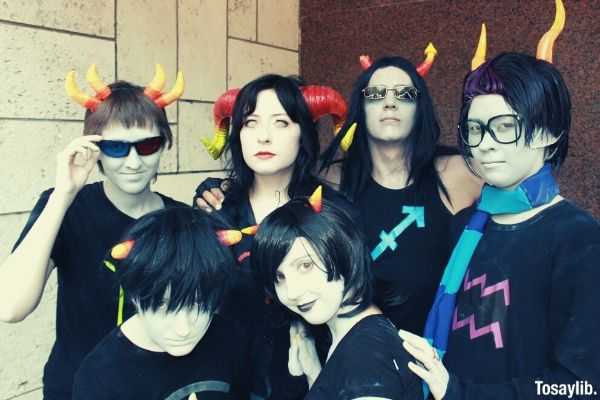 group of people wearing black halloween costumes group photo near concrete wall