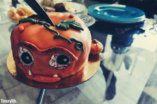 orange covered cake pumpkin themed on the table being sliced