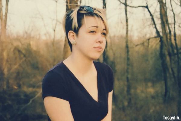 01 woman sad wearing black blonde hair sitting on a lying tree trunk