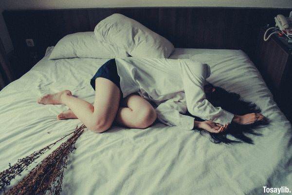 03 woman in white long sleeves and shorts sad lying on white bed