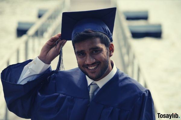man graduate holding his graduation cap smiling happy