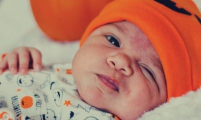 baby-wearing-orange-knitted-cap-photo-lying-near-pumpkin
