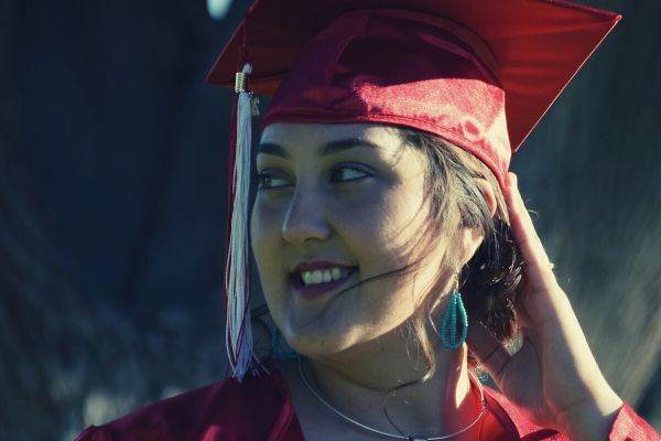 woman wearing red academic dress smiling looking at the right side