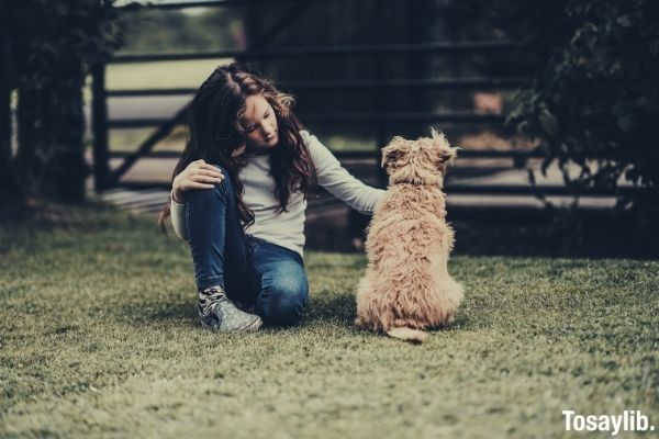 girl petting dog ADHD emotional support animal sitting on the grass