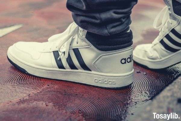 white and black adidas low top sneakers on wet floor