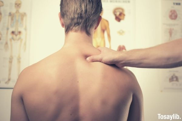 shirtless man having stabbing pain on the back therapist massaging him
