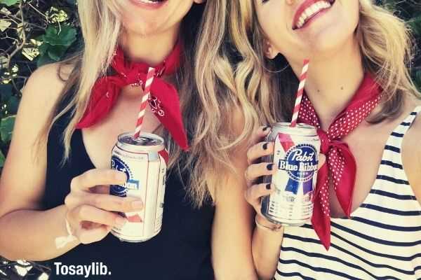 two women drinking pabst blue ribbon beverage wearing red handkerchief on neck